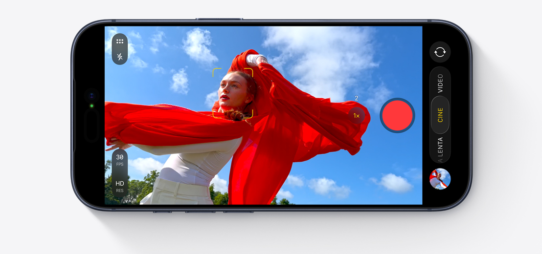 Parte frontal de un iPhone, en horizontal, en pantalla se está grabando un videoselfie de dos personas en un auto con la cámara frontal Center Stage, y unos cuadrados amarillos que encierran los rostros de las personas muestran el encuadre automático