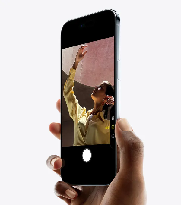 一隻手握著 iPhone Air，拇指按著相機控制按鈕，機身正面側斜展示纖薄外型、動態島、側邊按鈕