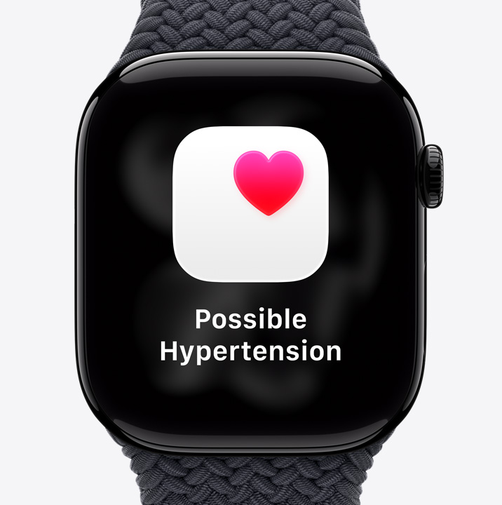Apple Watch Series 11，拋光亮黑色鋁金屬錶殼，配搭黑色編織單圈手環，螢幕顯示疑似高血壓健康通知，以及白色盒子內有粉紅色心心的圖示；右側外觀、數碼錶冠
