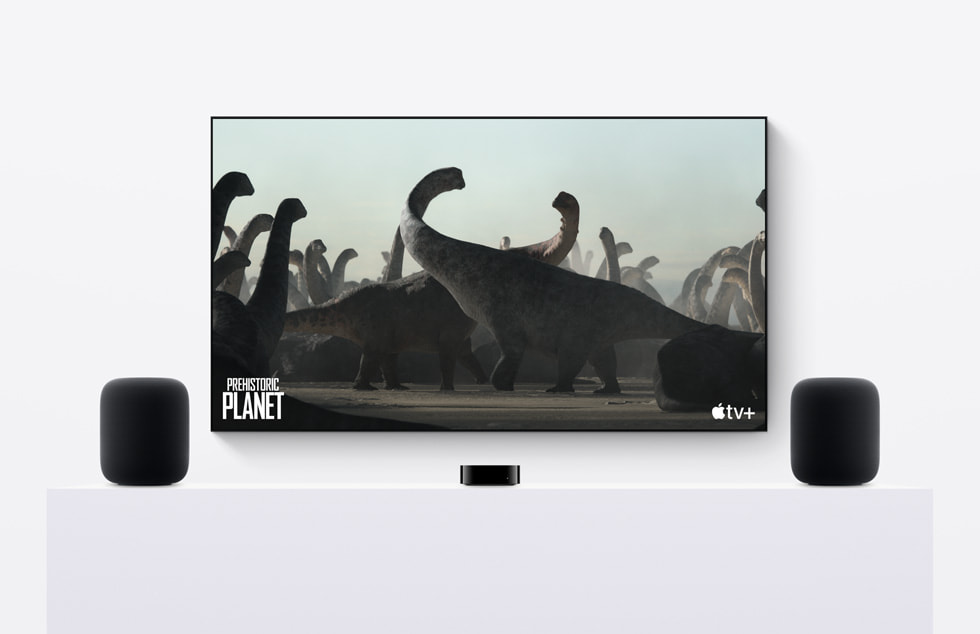 Et par HomePod-højttalere (2. generation) ved siden af Apple TV, hvor Prehistoric Planet afspilles på Apple TV+.