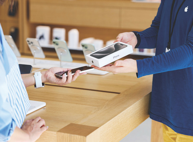 Apple Trade In 과정을 보여주는 이미지. 고객이 사용하던 iPhone을 상자에 담긴 새로운 iPhone과 교환하는 모습을 볼 수 있다.