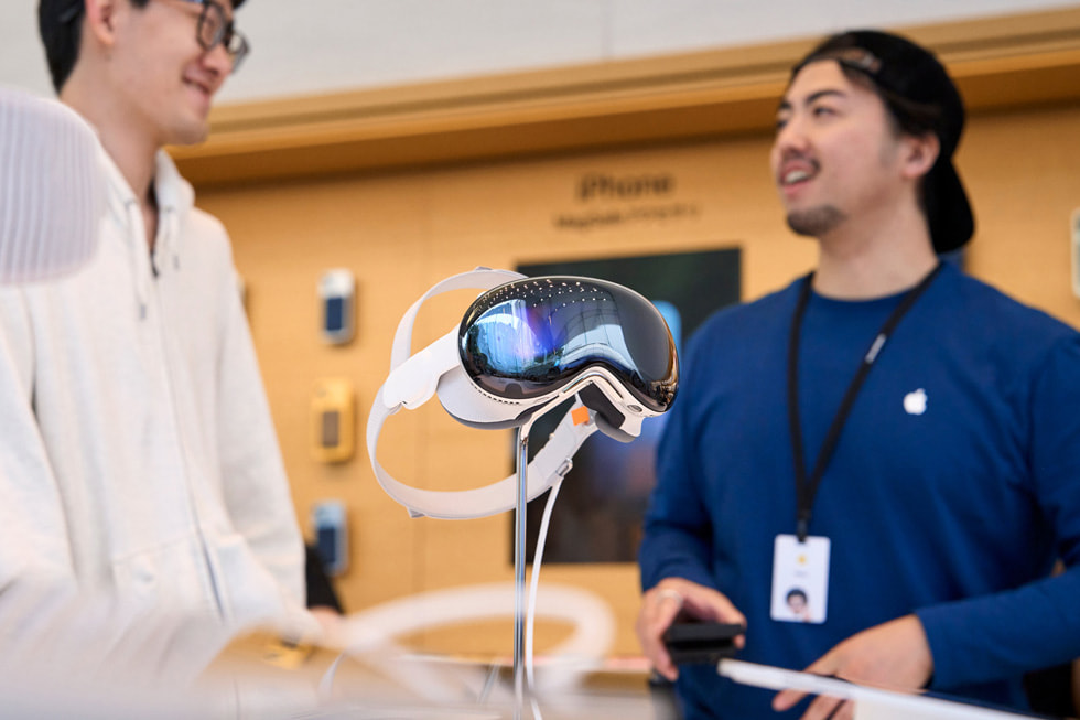 Un cliente y un integrante del equipo conversan cerca del exhibidor del Apple Vision Pro.