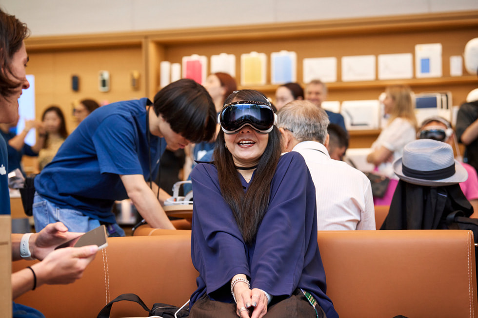 Una clienta sonríe y junta las manos al probar el Apple Vision Pro en la zona de prueba en Apple Omotesando.