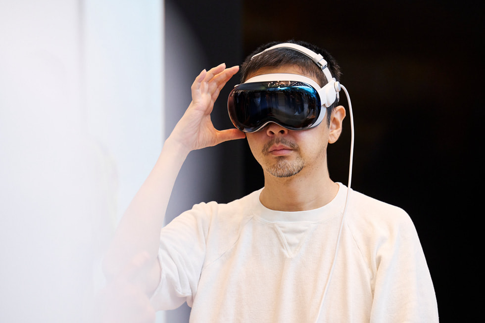 Un cliente con un Apple Vision Pro tiene una mano junto a su cabeza en Apple Omotesando.