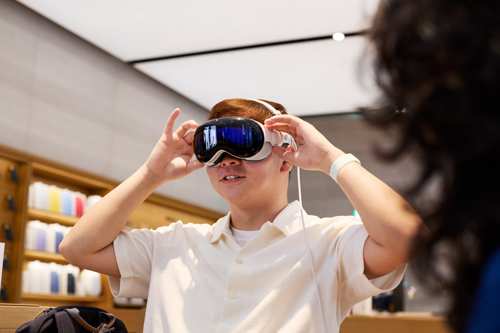 Un cliente con un Apple Vision Pro sostiene ambas manos junto a su cabeza.