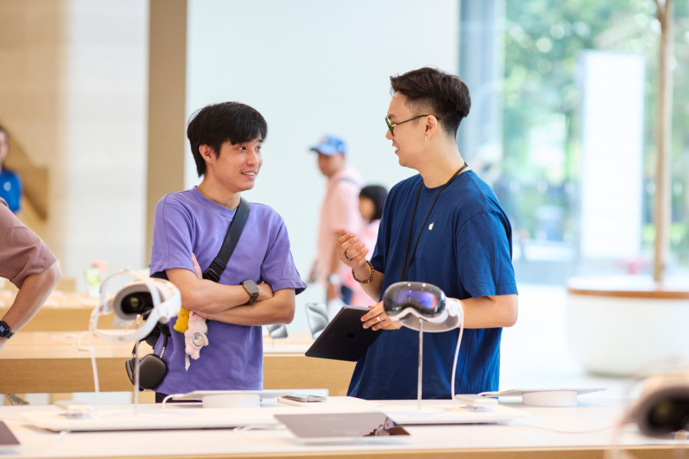 Un cliente y un integrante del equipo parados junto al exhibidor del Apple Vision Pro.