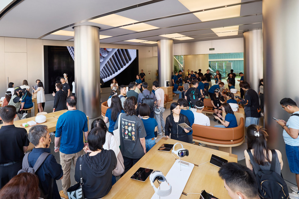 Foto panorámica del interior de Apple Wangfujing en la que se ve a los clientes dentro de la tienda y la zona de pruebas en el fondo.