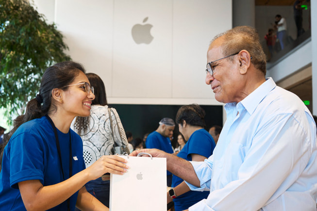 إحدى أعضاء فريق Apple تساعد عميلاً في عملية شرائه.