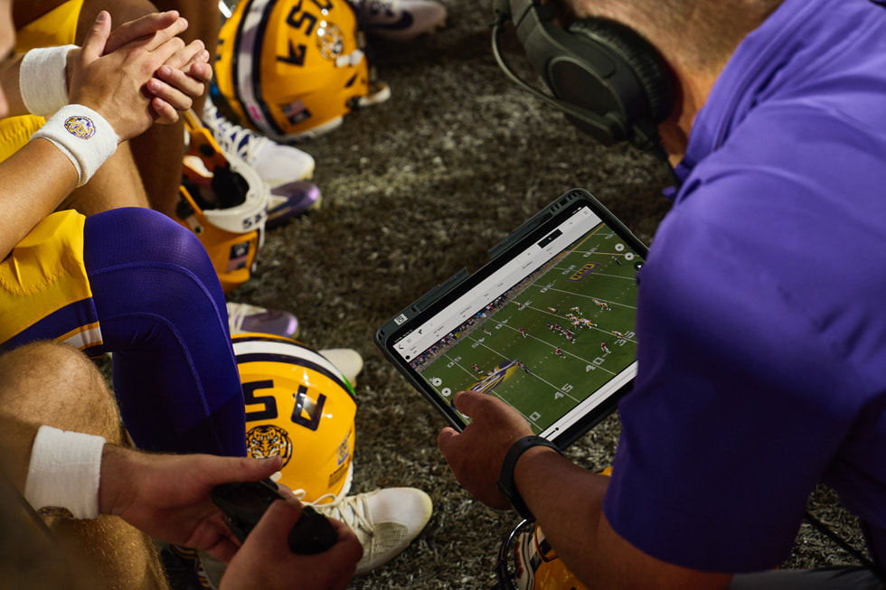 El equipo técnico y los jugadores de LSU revisan las grabaciones en un iPad Pro durante un partido de fútbol americano.