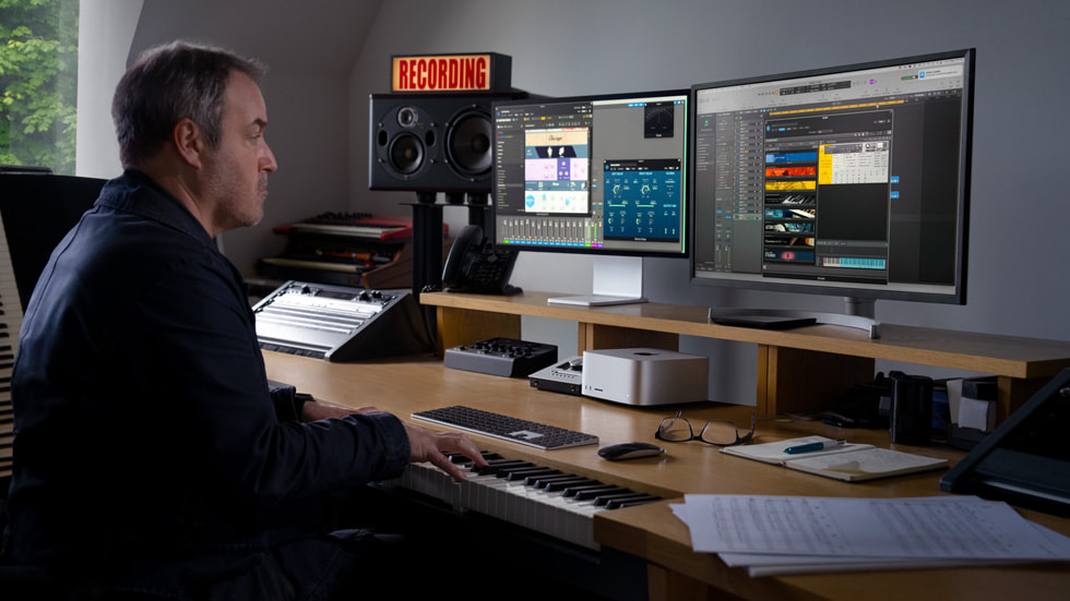 Un profesional trabajando en su escritorio con múltiples monitores conectados a la Mac Studio.