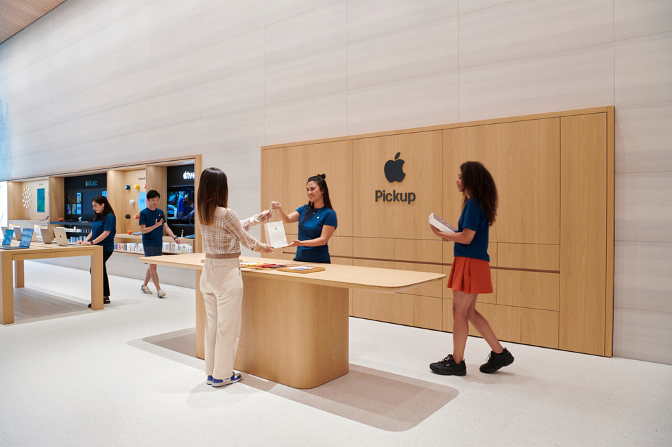 Un membre de l'équipe Apple remet un sac à une personne dans l'espace Apple Pickup à l'intérieur d'Apple Brompton Road.