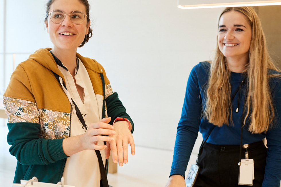 عميلة ترتدي ساعة Apple Watch تقارن ساعتها بموديل معروض لساعة Apple Watch في متجر Apple Champs-Élysées.