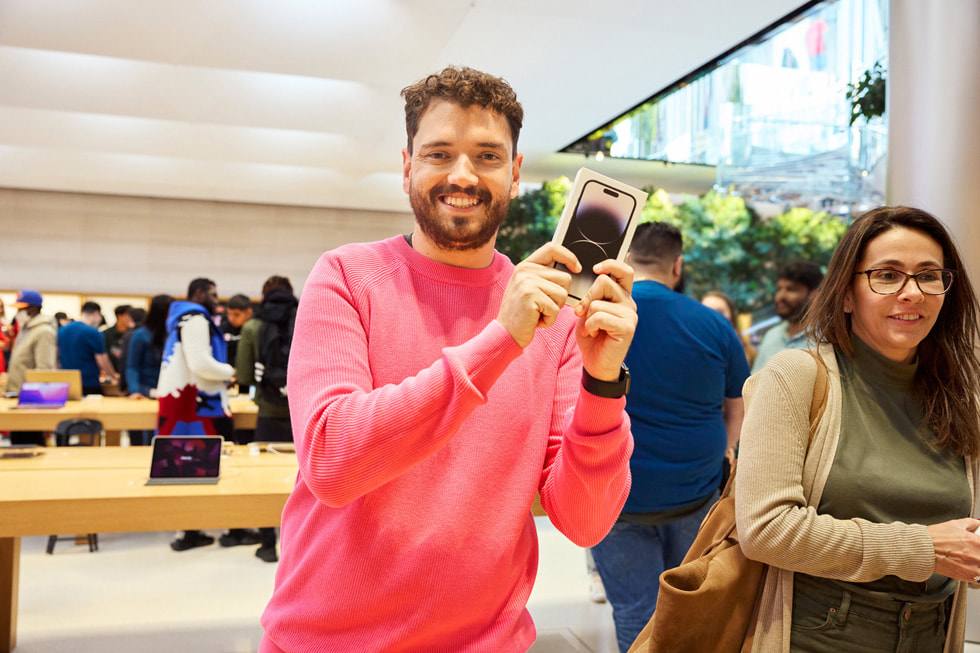 عميل يمسك بجهاز iPhone 14 Pro الجديد بكل سعادة لالتقاط صورة. 