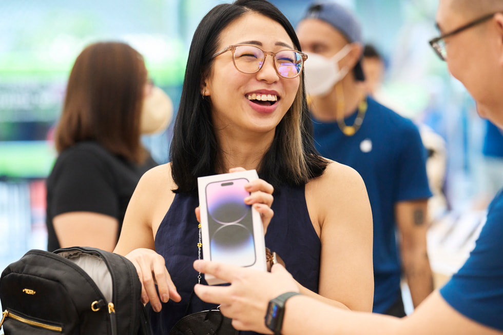 عميلة في متجر Apple Orchard Road تستلم من أحد أعضاء الفريق iPhone 14 Pro اشترته من المتجر.