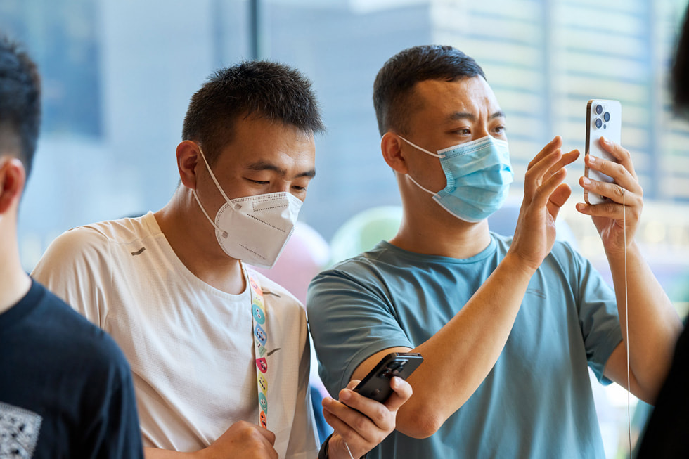 عميلان في متجر Apple Sanlitun يجرّبان Phone 14 Pro.