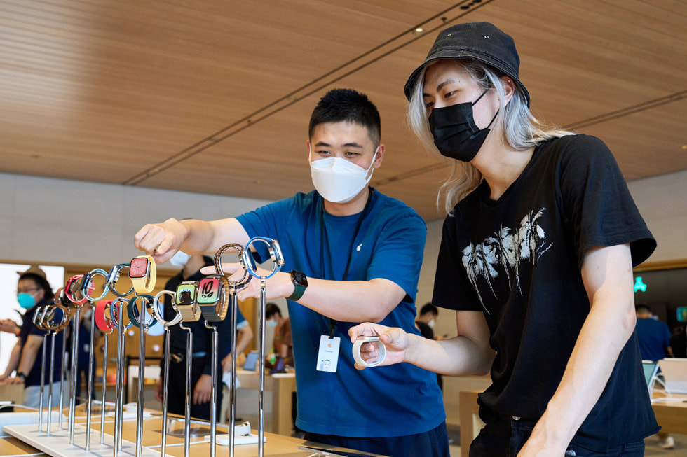 أحد أعضاء فريق متجر Apple Sanlitun يعرض ساعات Apple Watch لعميل.