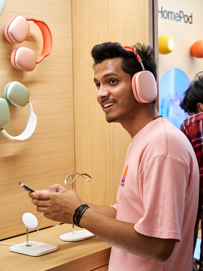 En kunde prøver AirPods Max ved et utstillingsbord i butikken.