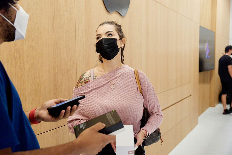 En medarbejder i Apple Bay Plaza hjælper en kunde med at købe en iPhone 13 Pro.