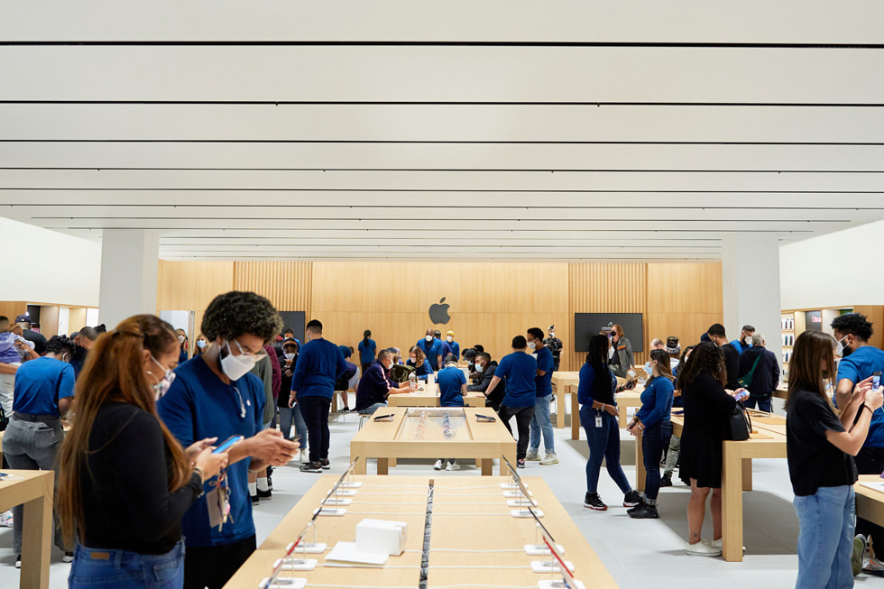 Kunder og Apple-medarbejdere omkring udstillingsborde hos Apple Bay Plaza.