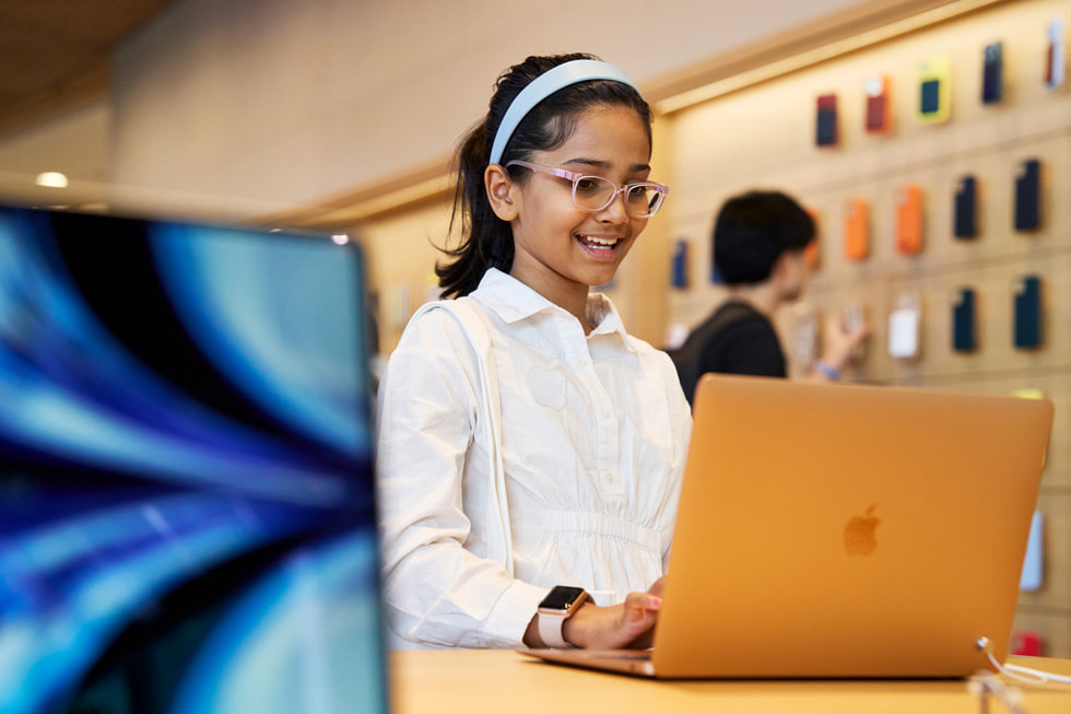 Młoda klientka korzysta z MacBooka Air wewnątrz salonu Apple BKC.