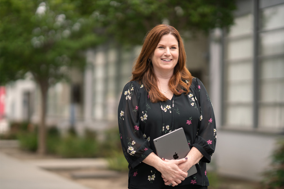 Jennifer Robbins, Downey Unified’s director of elementary education and an Apple Learning Coach, stands outdoors holding an iPad.