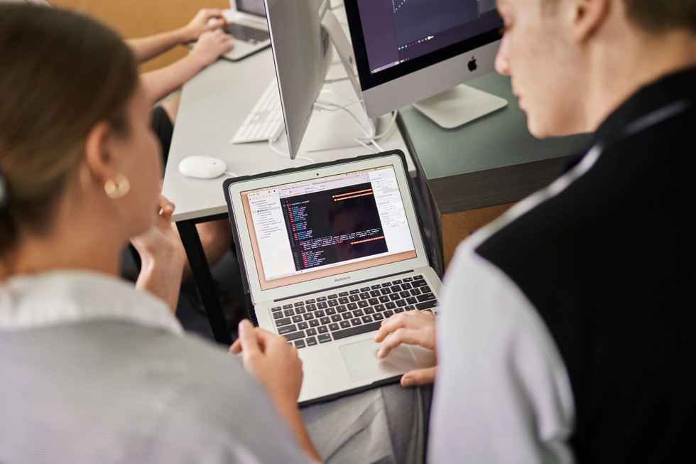 A Siena Catholic College student and instructor review code on MacBook Air.