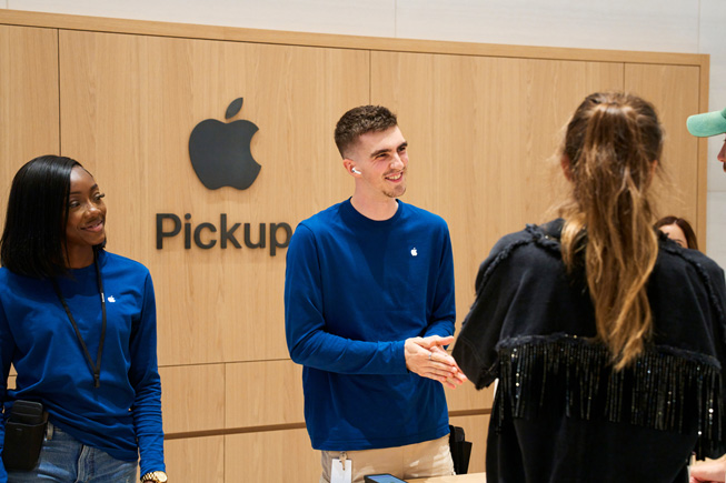 Apple-ansatte hjelper kunder med å hente bestillingene sine i et henteområde i en Apple Store.