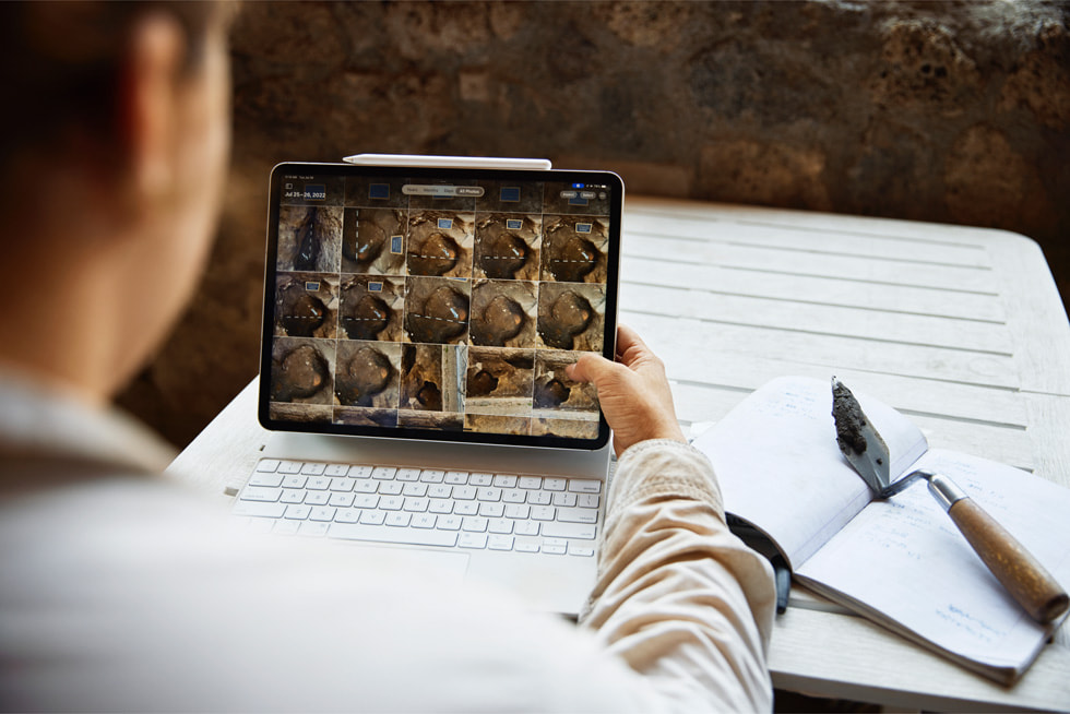iPad Proで発掘画像を確認する考古学者を後ろから肩越しに撮影した写真。