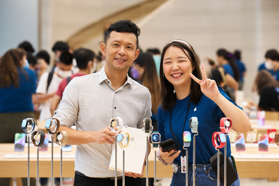 أحد عملاء متجر Apple Orchard Road يلتقط صورة مع مشترياته وأحد أعضاء الفريق بالقرب من منطقة عرض Apple Watch.