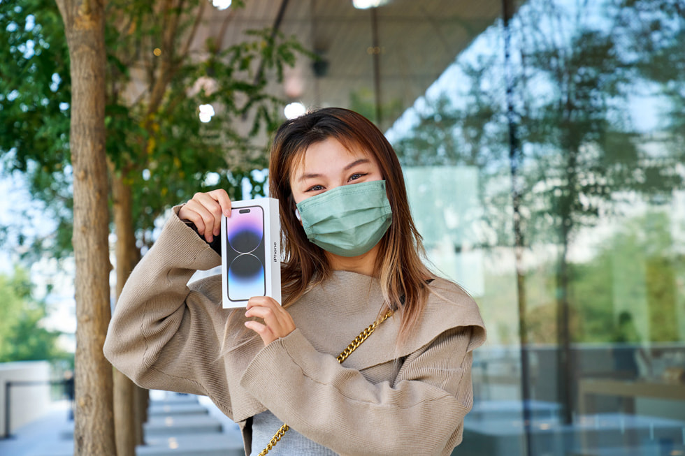 سيدة تمسك بجهاز iPhone 14 Pro الذي اشترته خارج متجر Apple Sanlitun.