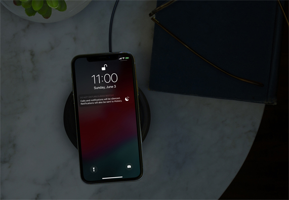 어두운 실내에서 방해 금지 모드 상태로 무선 충전 중인 iPhone 