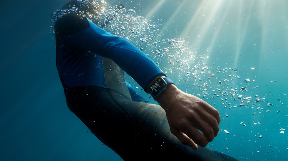 바다에서 손목에 찬 Apple Watch Series 7을 보고 있는 서퍼.